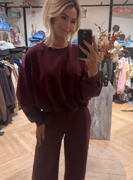 Model draagt bordeaux matching set sweater en broek